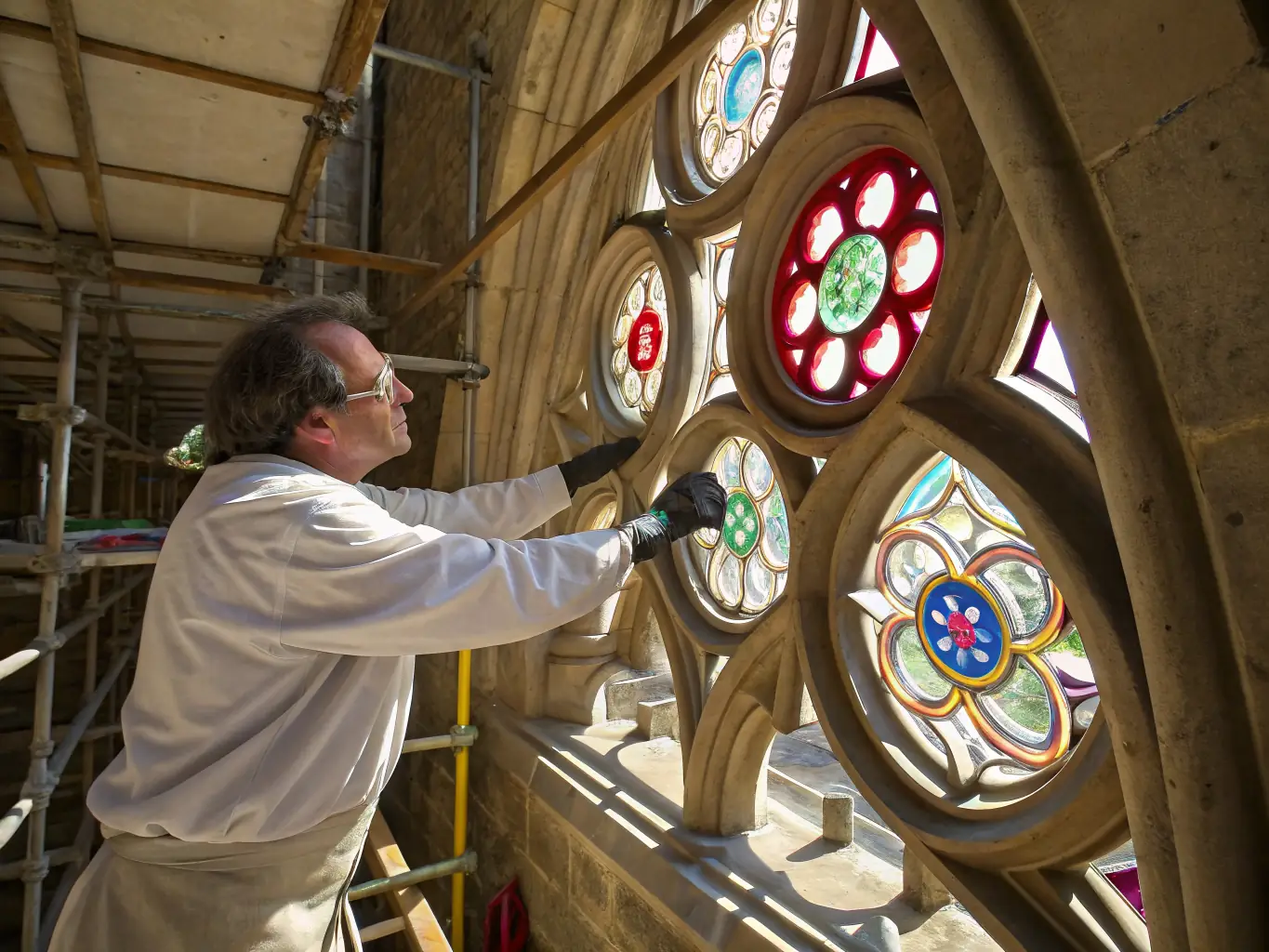A photograph showcasing the meticulous work being done on the church's stained glass windows, with artisans carefully piecing together fragments and restoring the vibrant colors.